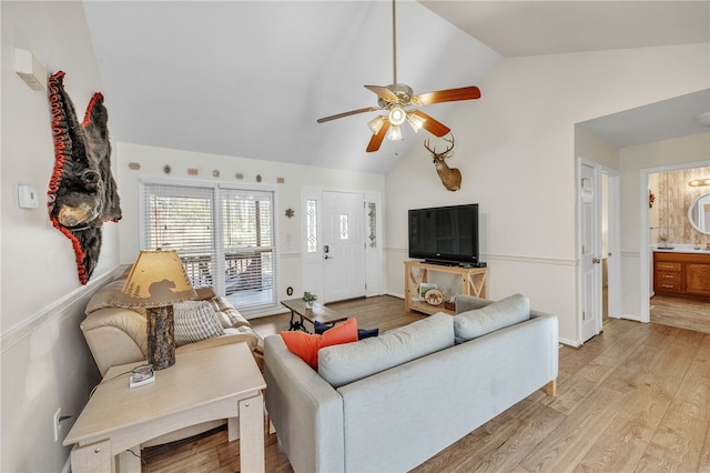 living area with high vaulted ceiling, a ceiling fan, and light wood-type flooring