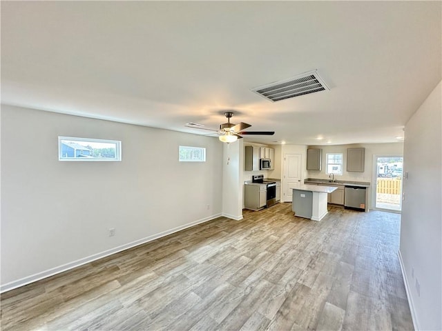kitchen featuring light countertops, gray cabinets, light wood-type flooring, a kitchen island, and appliances with stainless steel finishes