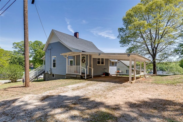 view of front of property featuring a chimney, driveway, and a carport