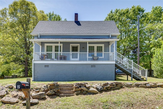 view of front of property with a chimney, covered porch, a front yard, roof with shingles, and stairs