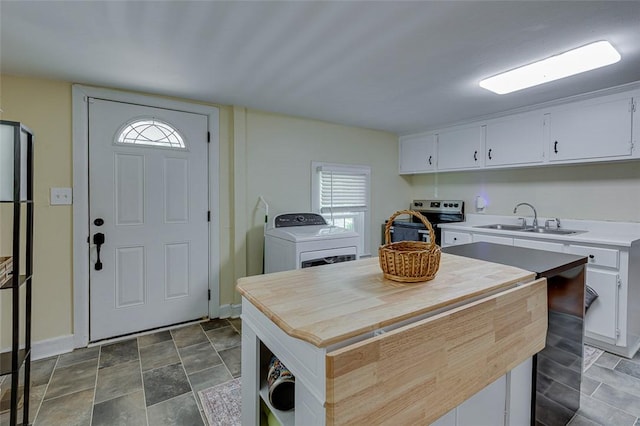 kitchen featuring a sink, stainless steel range with electric stovetop, washer / dryer, baseboards, and white cabinetry