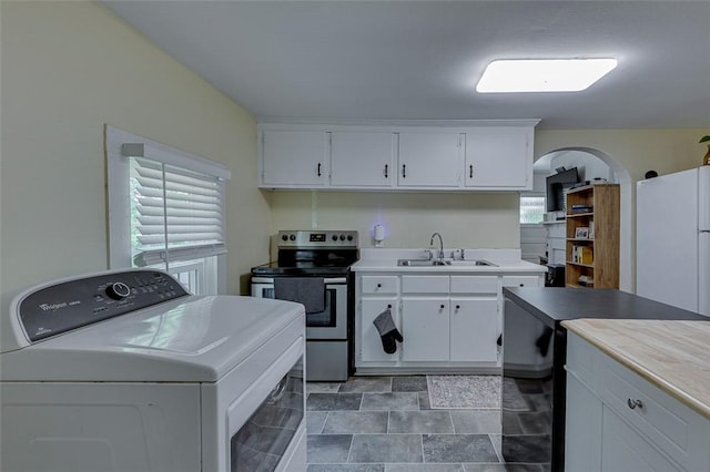 kitchen featuring a sink, stainless steel electric range, washer / dryer, white cabinets, and freestanding refrigerator