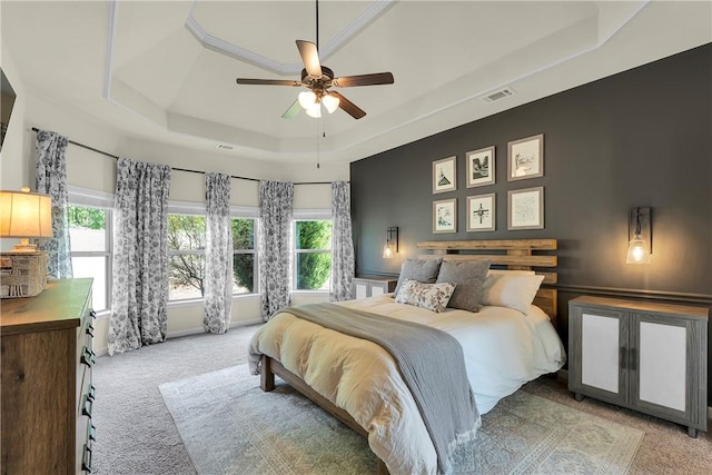 bedroom featuring a ceiling fan, carpet flooring, visible vents, and a raised ceiling