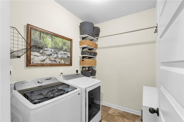 laundry area with washing machine and clothes dryer, baseboards, stone finish flooring, and laundry area