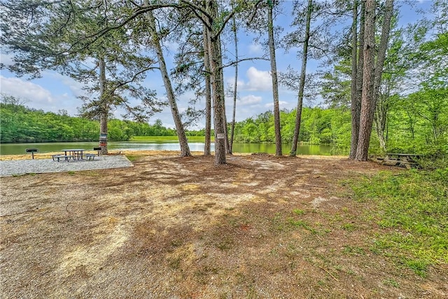 view of yard with a forest view and a water view