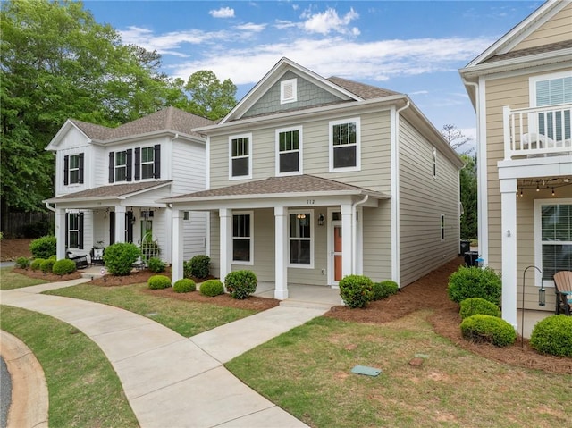 view of front of home featuring a front lawn, roof with shingles, and a porch