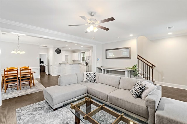 living area featuring dark wood-style floors, visible vents, ceiling fan with notable chandelier, stairway, and ornamental molding