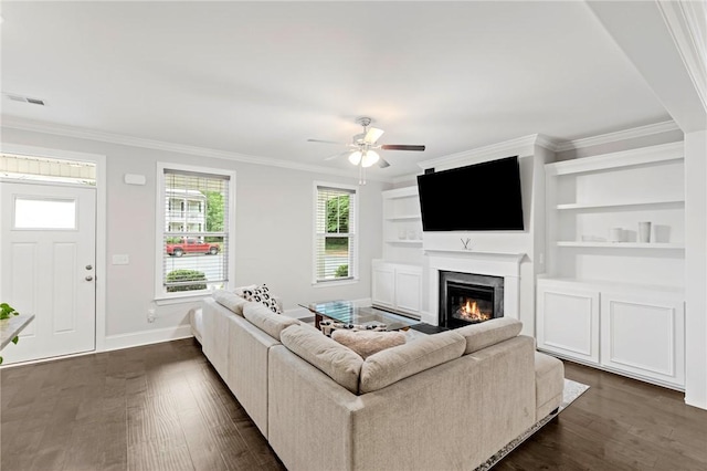living room featuring dark wood finished floors, crown molding, baseboards, and ceiling fan