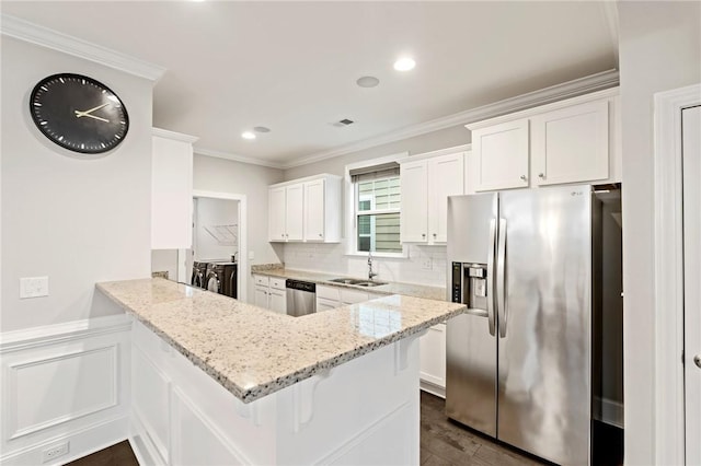 kitchen with white cabinets, stainless steel appliances, backsplash, light stone countertops, and a peninsula