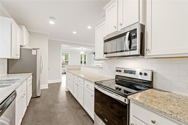 kitchen featuring tasteful backsplash, stainless steel appliances, white cabinets, baseboards, and ornamental molding
