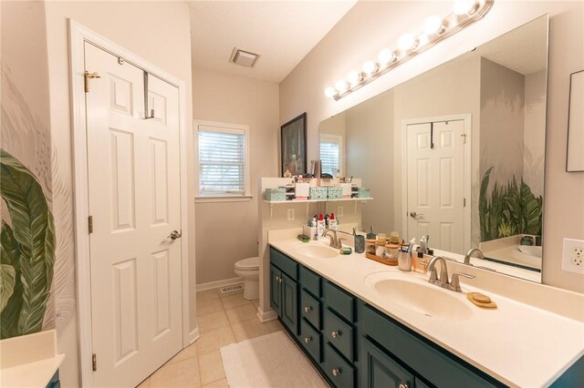 bathroom featuring baseboards, toilet, tile patterned flooring, and a sink