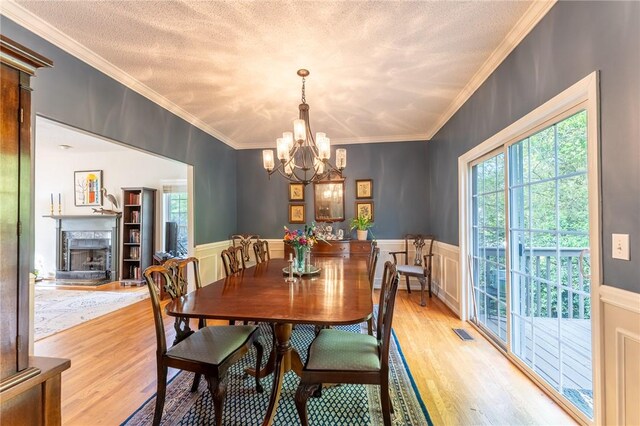 dining area with a high end fireplace, visible vents, ornamental molding, light wood-style floors, and a notable chandelier