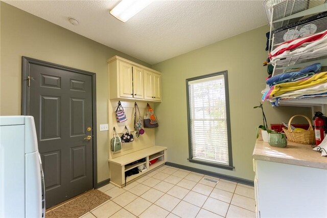 mudroom with a textured ceiling, baseboards, visible vents, light tile patterned floors, and washer / dryer
