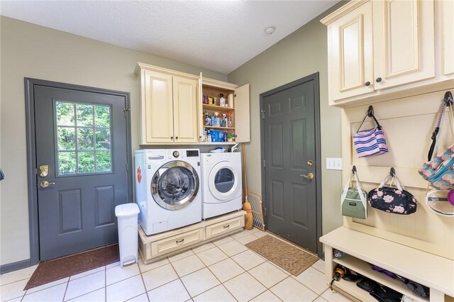 washroom with washing machine and dryer, light tile patterned floors, and cabinet space