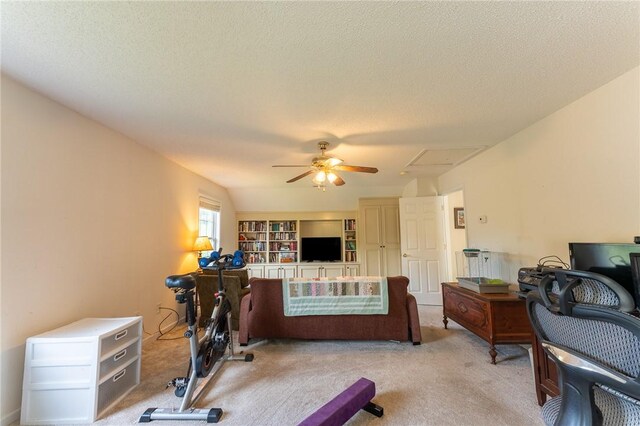 workout room with light carpet, a ceiling fan, and a textured ceiling