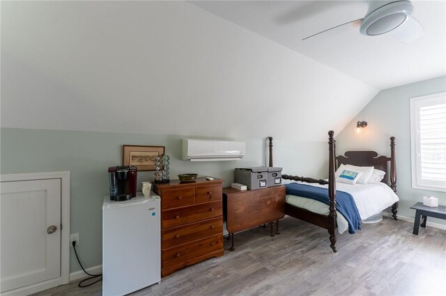 bedroom with a ceiling fan, wood finished floors, baseboards, lofted ceiling, and a wall unit AC
