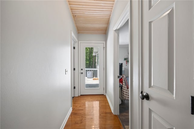 doorway with wood ceiling, baseboards, and light wood-style floors