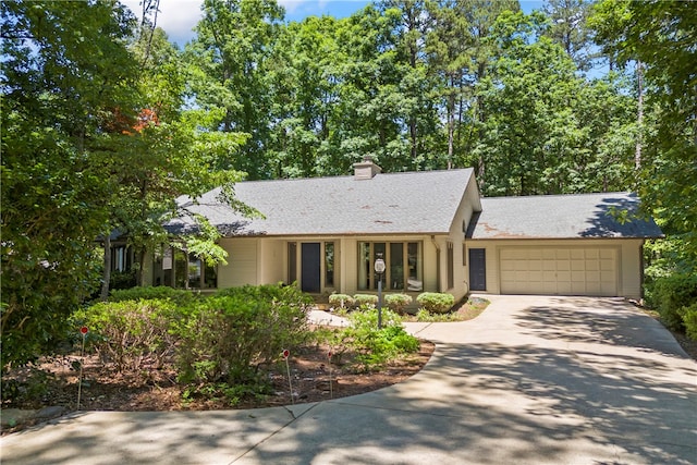 ranch-style home with concrete driveway, roof with shingles, a chimney, and a garage