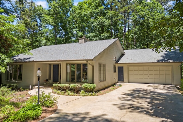 ranch-style home with a garage, driveway, a shingled roof, and a chimney