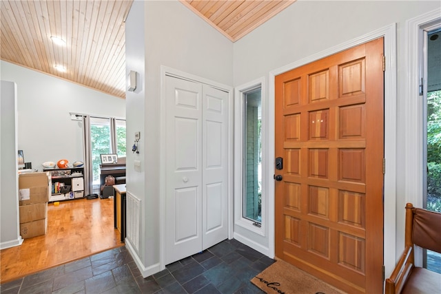 entrance foyer featuring baseboards, stone finish flooring, wood ceiling, and ornamental molding