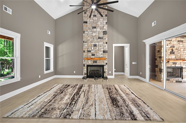 unfurnished living room with visible vents, high vaulted ceiling, ceiling fan, and a fireplace