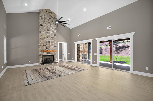 unfurnished living room with visible vents, wood finished floors, a ceiling fan, high vaulted ceiling, and a stone fireplace