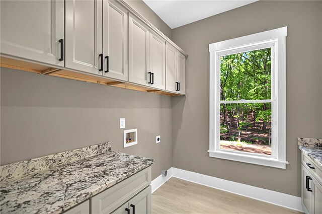 washroom with hookup for a washing machine, electric dryer hookup, light wood-style floors, cabinet space, and baseboards