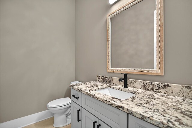 bathroom featuring baseboards, toilet, and vanity