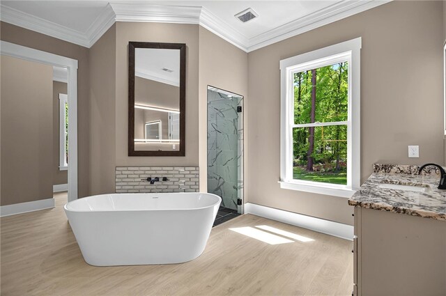 bathroom featuring a freestanding tub, wood finished floors, a shower stall, and ornamental molding
