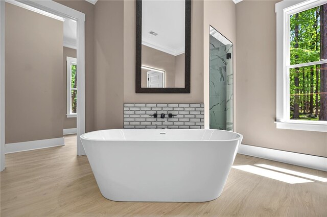 bathroom featuring a freestanding tub, wood finished floors, and ornamental molding