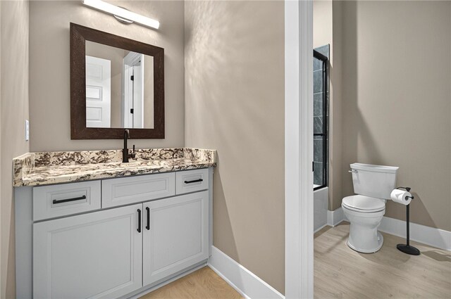 full bath with vanity, shower / bath combination, toilet, baseboards, and wood finished floors