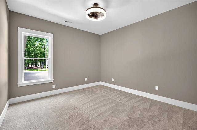 spare room featuring baseboards, visible vents, and carpet flooring