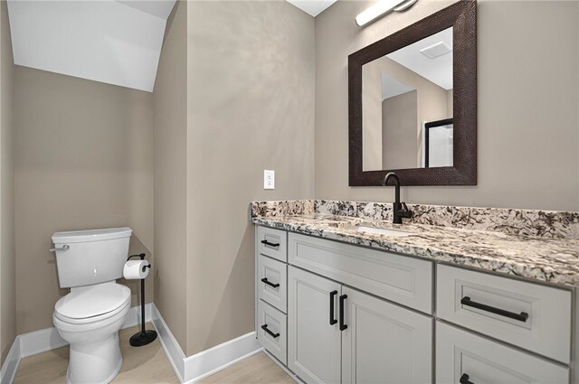 bathroom featuring baseboards, toilet, and vanity