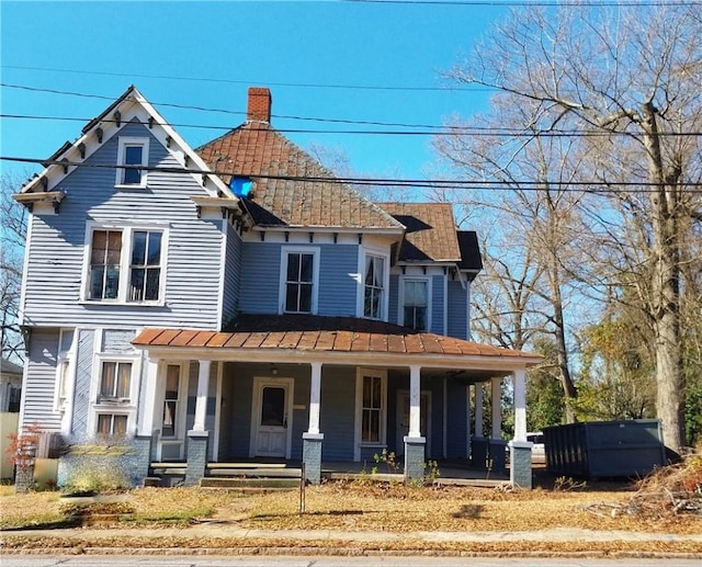 victorian-style house with a porch, a standing seam roof, and metal roof