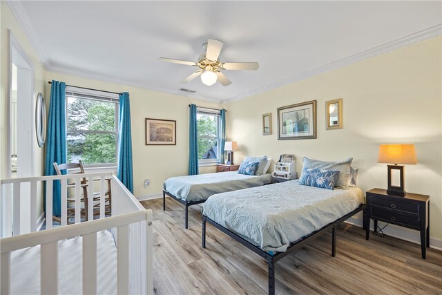 bedroom featuring crown molding, ceiling fan, visible vents, baseboards, and wood finished floors