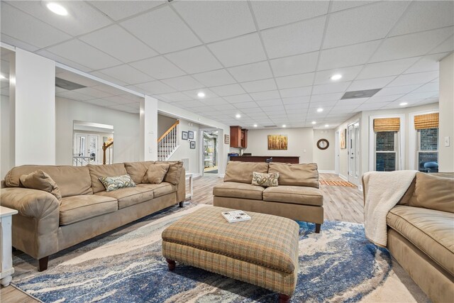 living room featuring baseboards, light wood-type flooring, stairs, and recessed lighting