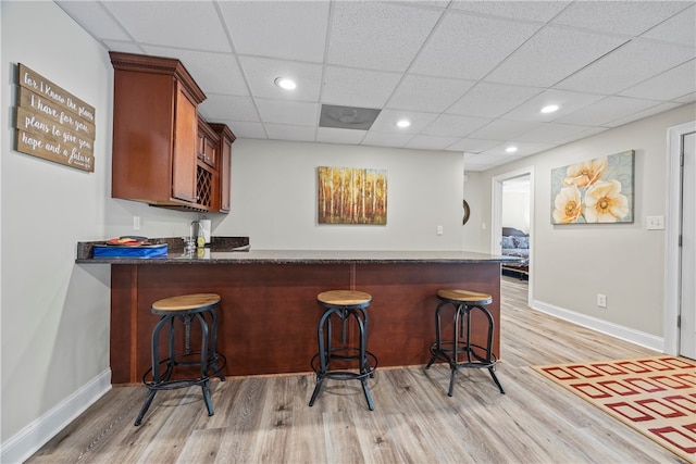 bar featuring baseboards, wet bar, light wood finished floors, and recessed lighting