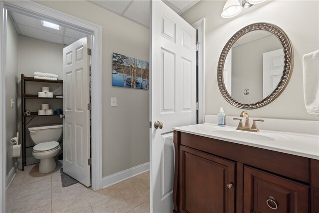 bathroom featuring toilet, tile patterned flooring, vanity, and baseboards