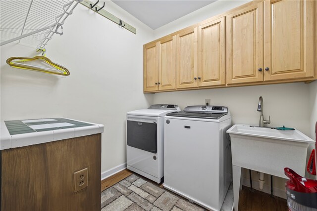 laundry area with light wood finished floors, cabinet space, baseboards, and washer and clothes dryer