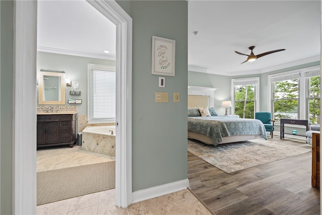 bedroom featuring baseboards, ensuite bath, multiple windows, and crown molding