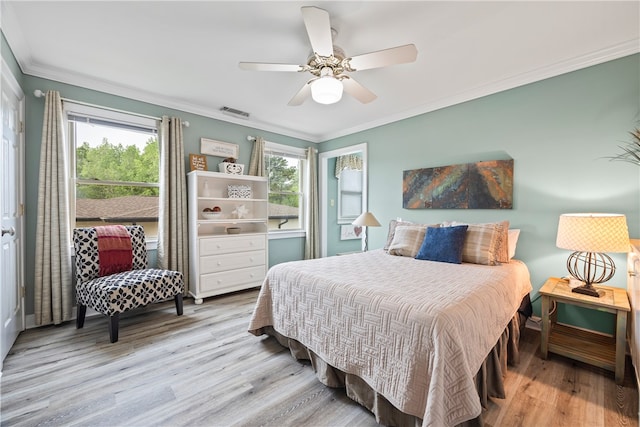 bedroom with wood finished floors, ceiling fan, ornamental molding, and multiple windows