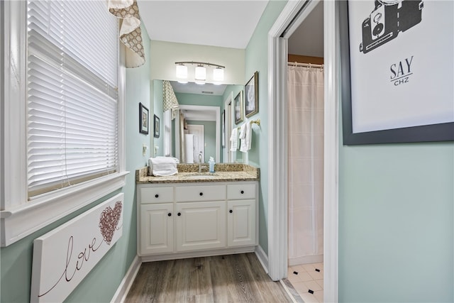bathroom with wood finished floors, vanity, and baseboards
