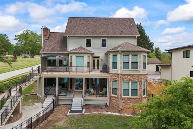 rear view of house with a wooden deck, a chimney, stairway, brick siding, and a fenced backyard