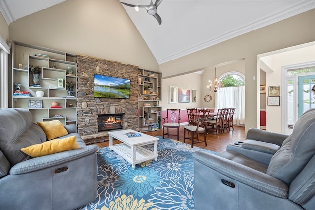 living room with wood finished floors, high vaulted ceiling, a stone fireplace, and ceiling fan with notable chandelier