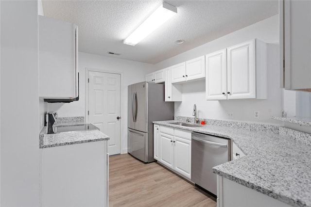 kitchen featuring a textured ceiling, white cabinetry, stainless steel appliances, and a sink