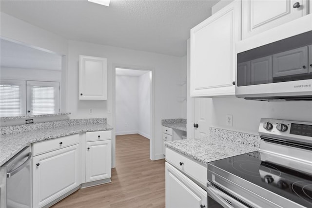 kitchen with a textured ceiling, white cabinetry, appliances with stainless steel finishes, baseboards, and light wood-type flooring