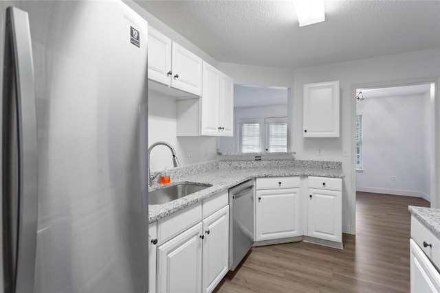 kitchen with white cabinets, wood finished floors, appliances with stainless steel finishes, and a sink