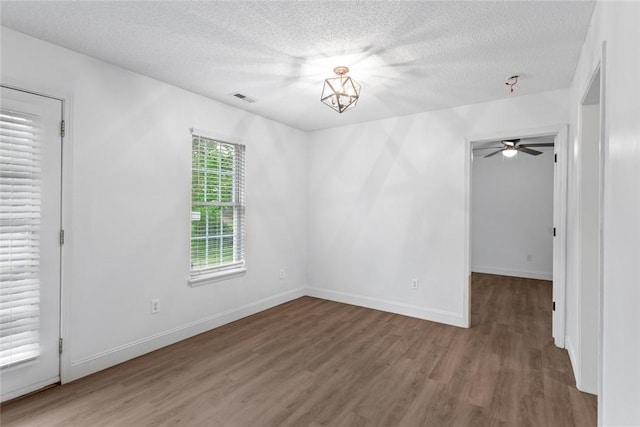 empty room with ceiling fan, visible vents, baseboards, a textured ceiling, and wood finished floors