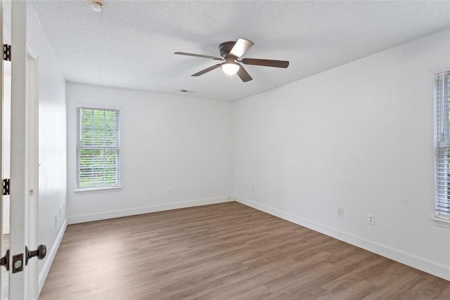 unfurnished room with baseboards, visible vents, ceiling fan, and light wood-style floors