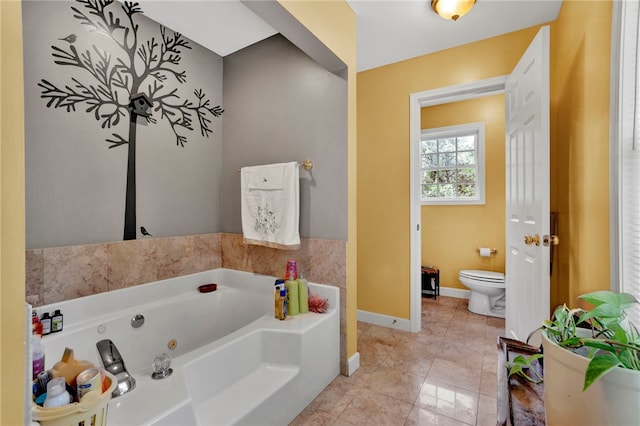bathroom with baseboards, toilet, and a jetted tub